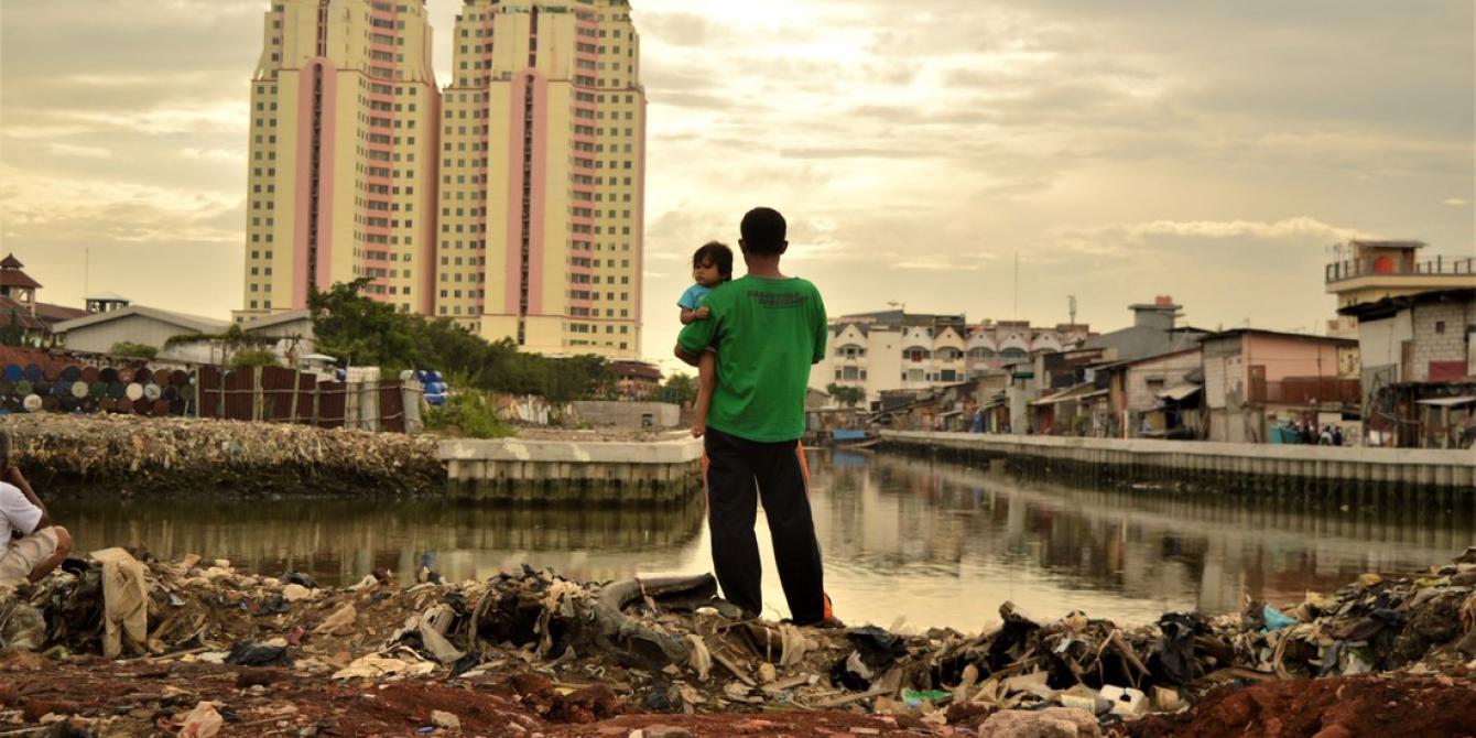 Menuju IndonesiaYang Lebih Setara Menatap masa depan: seorang ayah menggendong anak perempuannya ketika berdiri di satu area dimana warga setempat baru saja digusur untuk area pembangunan baru, dekat dengan apartemen mewah di Jakarta Utara, Indonesia. Dalam dua dekade terakhir, ketimpangan antara kelompok orang terkaya dan kelompok lainnya di Indonesia makin meningkat secara lebih cepat ketimbang negara lain di Asia Tenggara. Foto: Tiara Audina/Antropologi UI